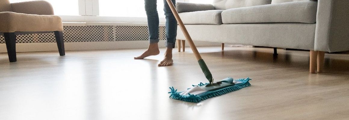 Frau putzt ihren Holzboden mit einem Wischer